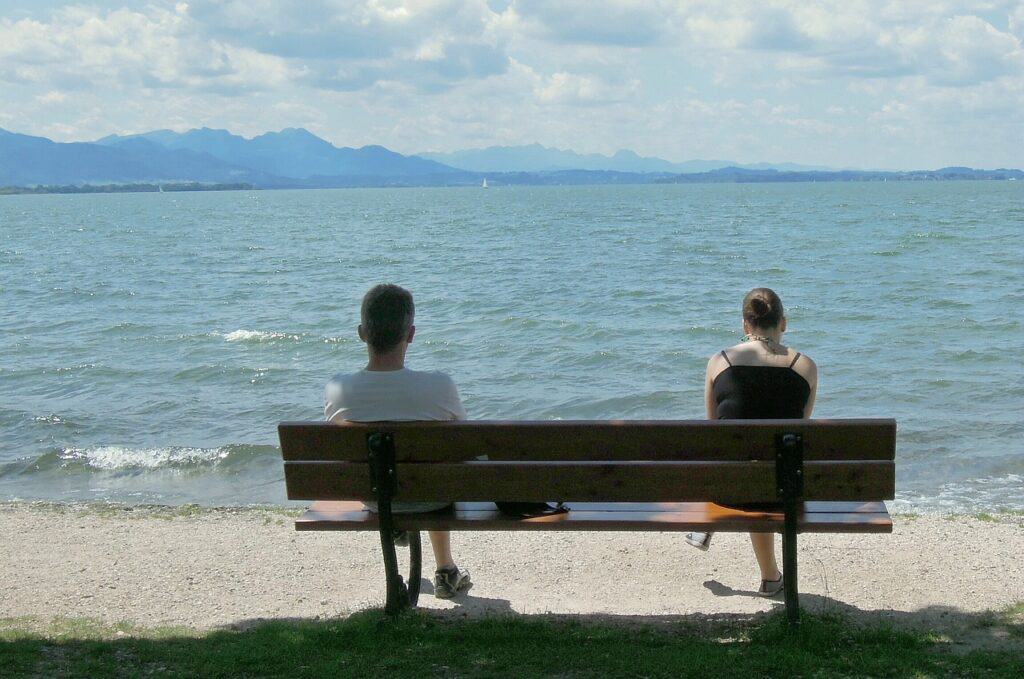 People sitting on opposite ends of a bench by the sea