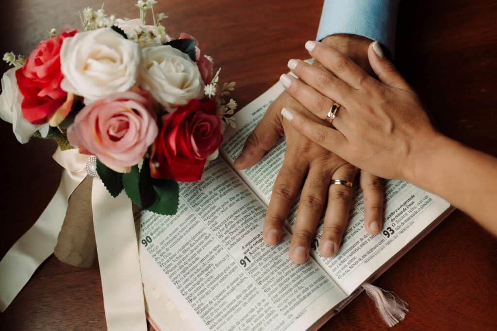 couple hands wearing wedding ring on Bible