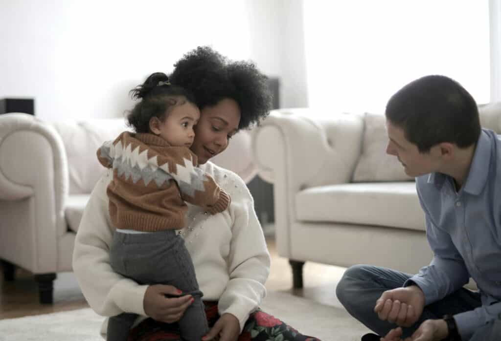 Mom holding toddler, man trying to talk to toddler